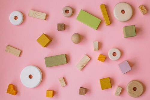Free Flatlay of various wooden shapes on a pastel pink background, perfect for creative and playful designs. Stock Photo