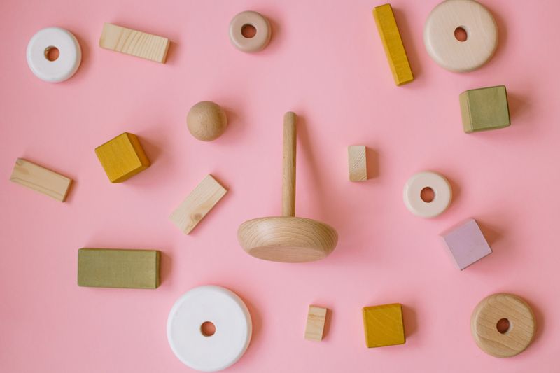 Wooden shapes and a spinning top on soft pink