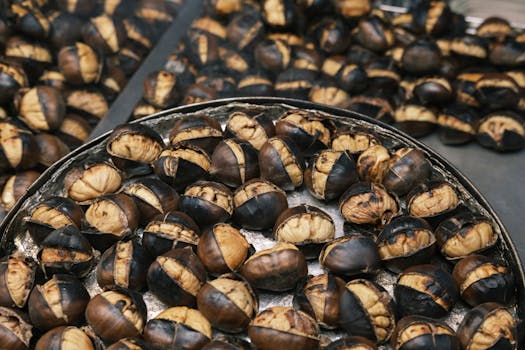 A detailed shot of roasted chestnuts arranged on a metal tray, showcasing their texture and color.
