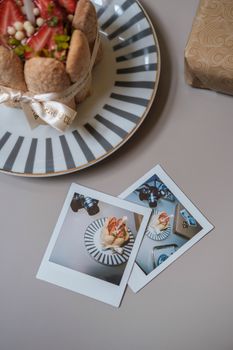 Top view of a dessert on a striped plate with Polaroid photos, styled elegantly.