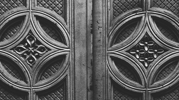 Detailed close-up of an ornate door design, showcasing intricate patterns in black and white.