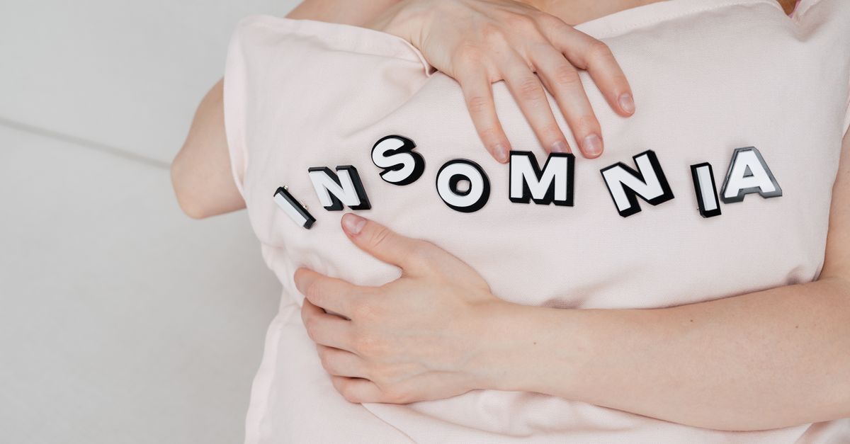 Close-up of a woman holding a pillow with 'insomnia' text, depicting sleep disorder. - Evidence evidence guide for magnesium insomnia randomized trial