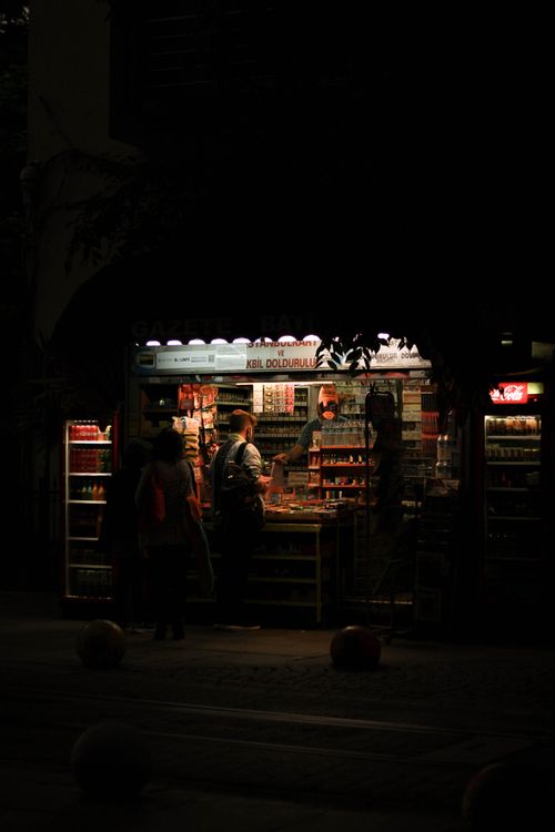 Free Interior view of a convenience store with warm lighting at night, showcasing the shelves and customers. Stock Photo