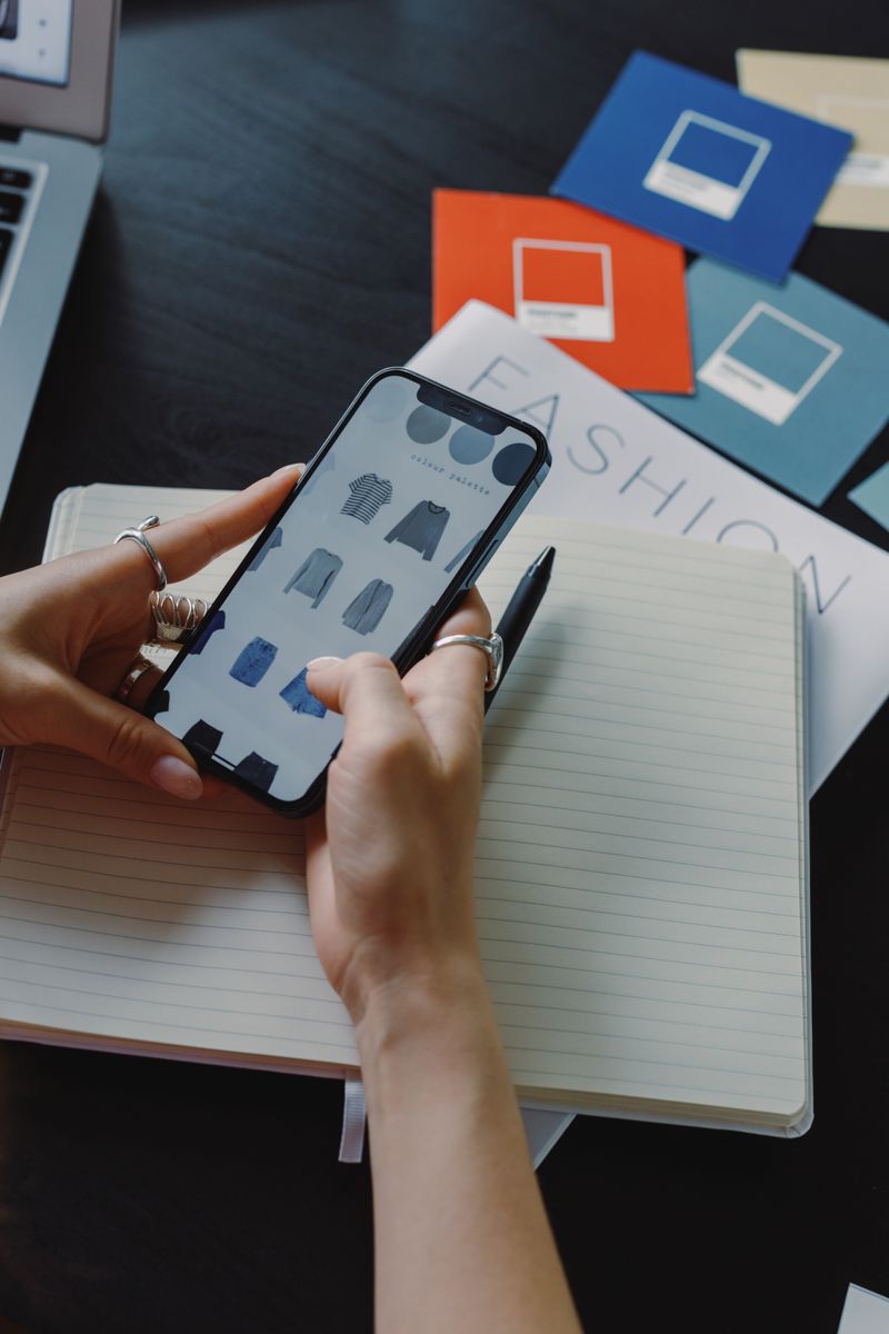 Woman browsing fashion products on a smartphone while sitting at a desk