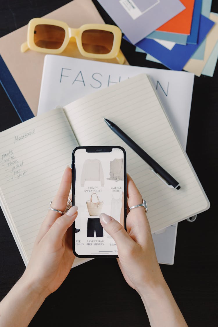 Close-up Of Woman Shopping Online On Cellphone Sitting At Desk