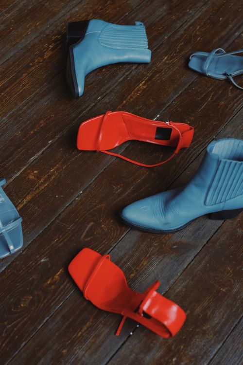 Free Close-up view of blue boots and red sandals on rustic wooden planks. Stock Photo