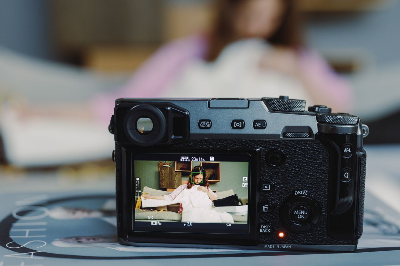 close up of a digital camera capturing a scene of a woman in a bedroom