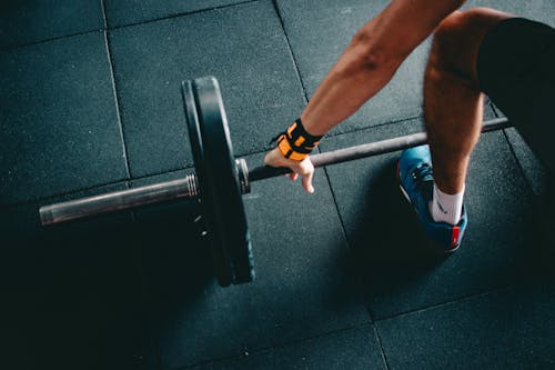 Free Person Wearing Black Shorts and Blue Lace-up Low-top Sneaker Holding Black Barbell Stock Photo