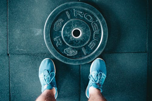 Free Black Steel Gym Plate and Pair of Blue Running Shoes Stock Photo