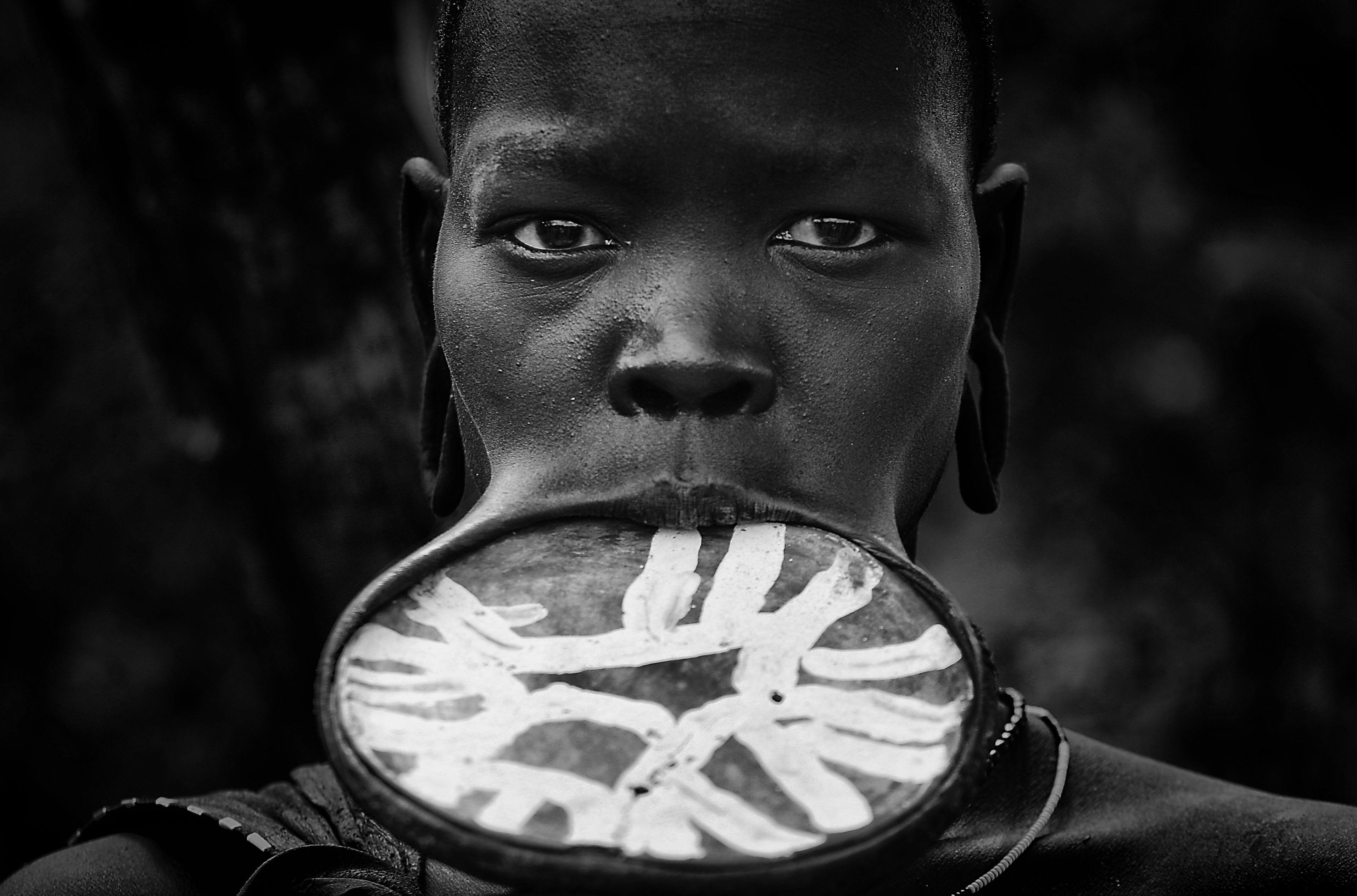 close up photo of man with clay plate inserted on his lips