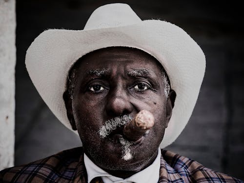 A Man Wearing a Hat Smoking a Cigar