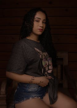 Stylish woman posing indoors in casual outfit with graphic tee.