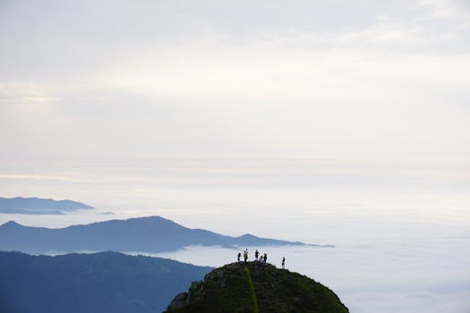 A scenic aerial view of hikers on a mountain peak in Rize, Türkiye, with clouds below.
