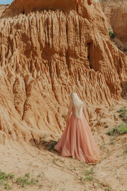 Backview of Woman in Pink Dress near a Sandstone 