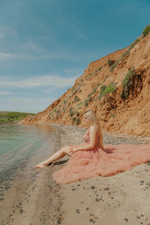 A Woman Wearing a Pink Dress Sitting on the Beach