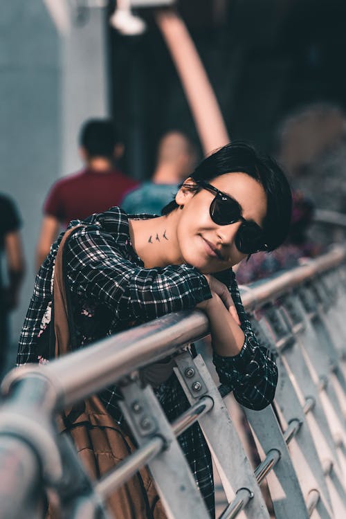 
A Tattooed Woman with Short Hair Leaning on a Railing