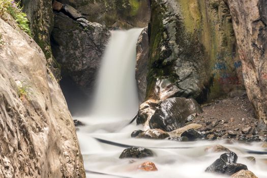 A peaceful waterfall flowing over rugged rocks, surrounded by nature's tranquility and beauty.