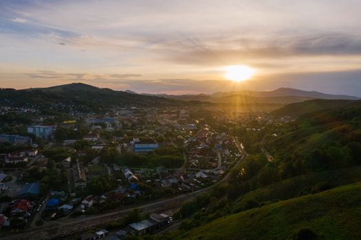 Scenic aerial view of a countryside town during sunset with rolling hills in the background.