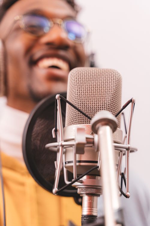 Free Close-up of a smiling singer recording with a microphone in a music studio setting. Stock Photo