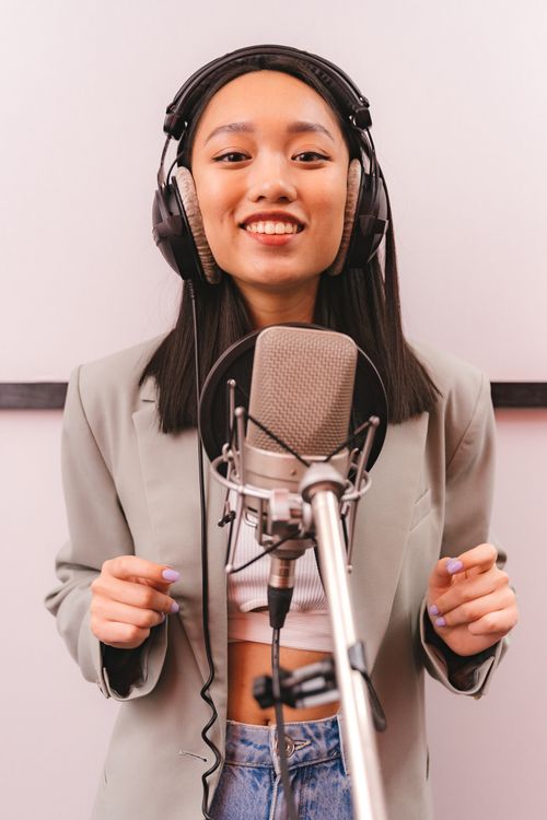 Free A stylish young woman singing joyfully in a recording studio wearing headphones, expressing creativity and passion. Stock Photo