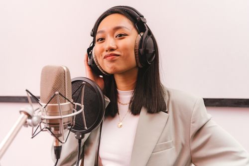 Free Young female singer wearing headphones in a studio setup with a microphone. Stock Photo