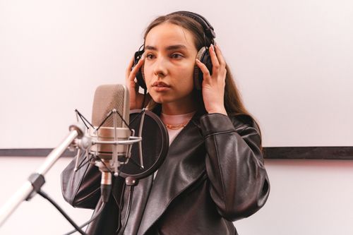 Free Woman in a leather jacket recording vocals in a professional studio. Stock Photo