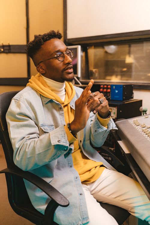 Free Man in casual attire working in a recording studio with mixing console. Stock Photo