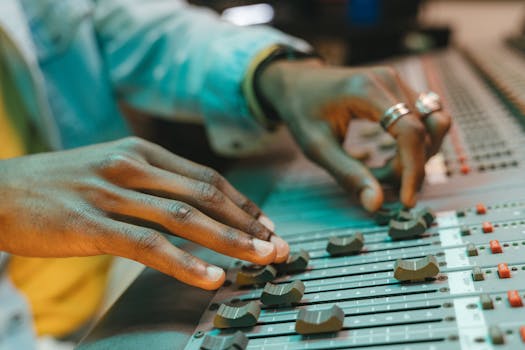 Close-up of a person expertly adjusting audio mixer controls in a music studio setting.