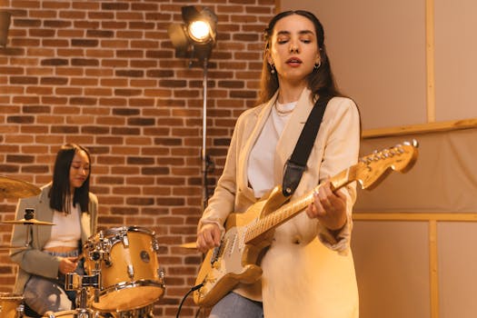 Two women musicians practicing with guitar and drums in a music studio.