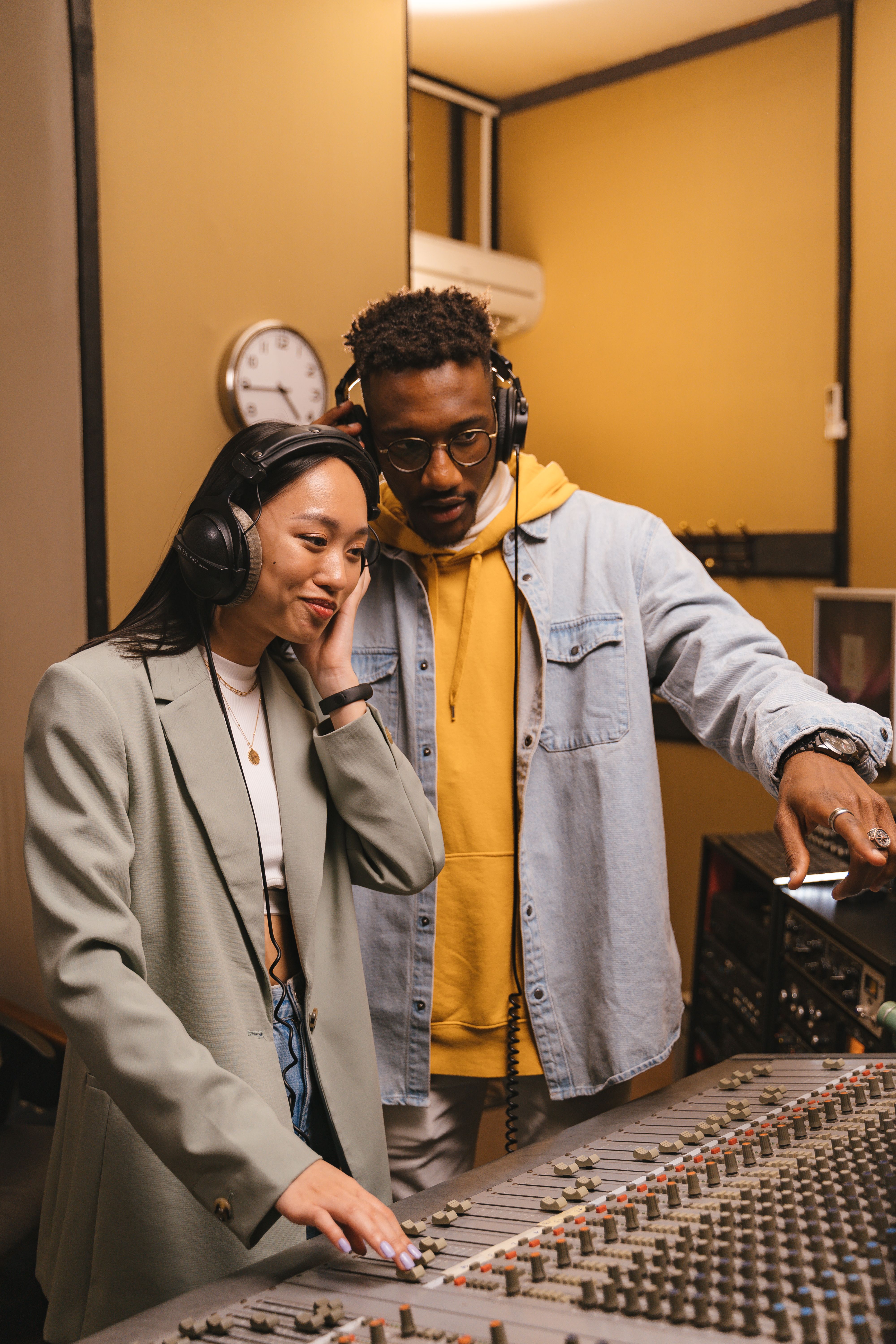 Two people wearing headphones working at an audio mixer