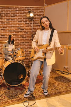 Two women playing guitar and drums in a music studio, exuding creativity and passion.