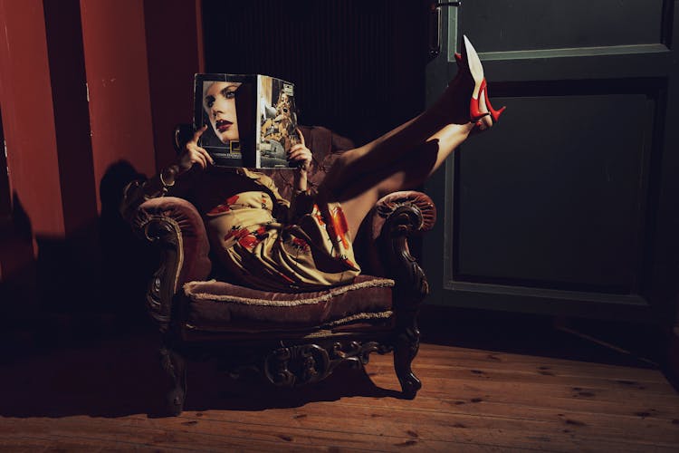 
A Woman Reading A Magazine While Sitting On A Chair