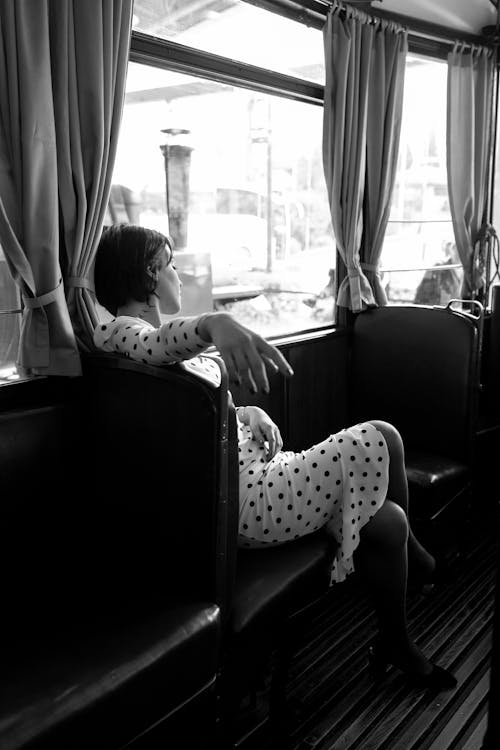 

A Grayscale of a Woman Wearing a Polka Dot Dress Sitting