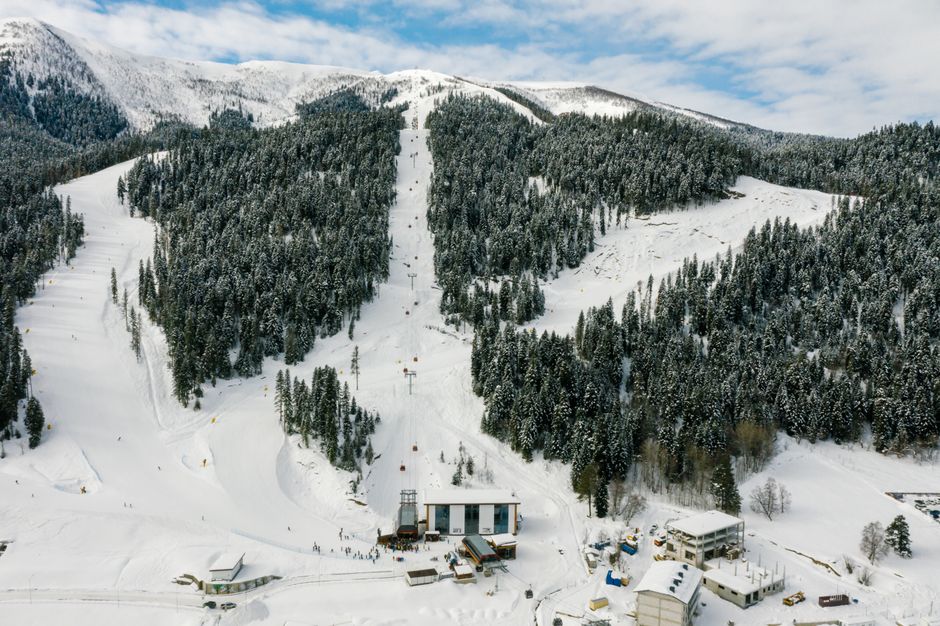 Stunning aerial view of a snowy ski resort surrounded by evergreen trees and mountains. Perfect for winter travel.