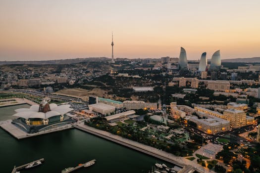 Aerial view of Baku's skyline featuring the Flame Towers and Caspian Sea at dusk.