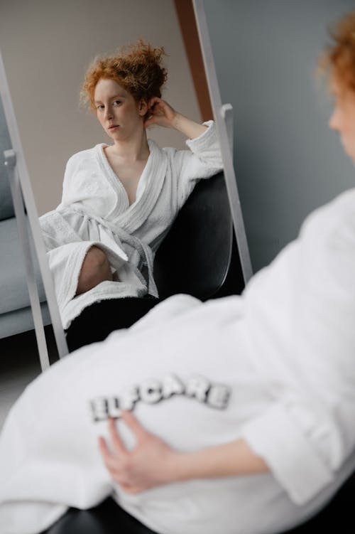 Woman in White Robe Sitting In Front of a Mirror