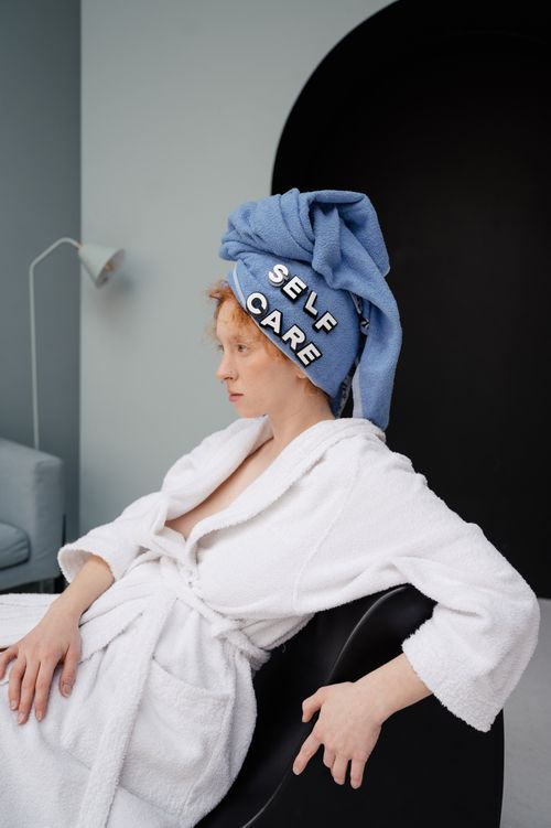 Free A woman seated in a bathrobe, relaxing with a towel wrapped on her head labeled 'self care'. Stock Photo