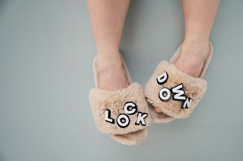 Free Close-up of beige furry slippers with 'lockdown' text, highlighting comfort and home lifestyle. Stock Photo