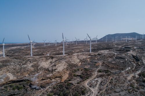 Free A drone captures wind turbines on a barren desert landscape under clear skies. Stock Photo