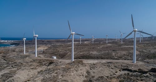 Wind Turbines on Brown Sand Under Blue Sky 