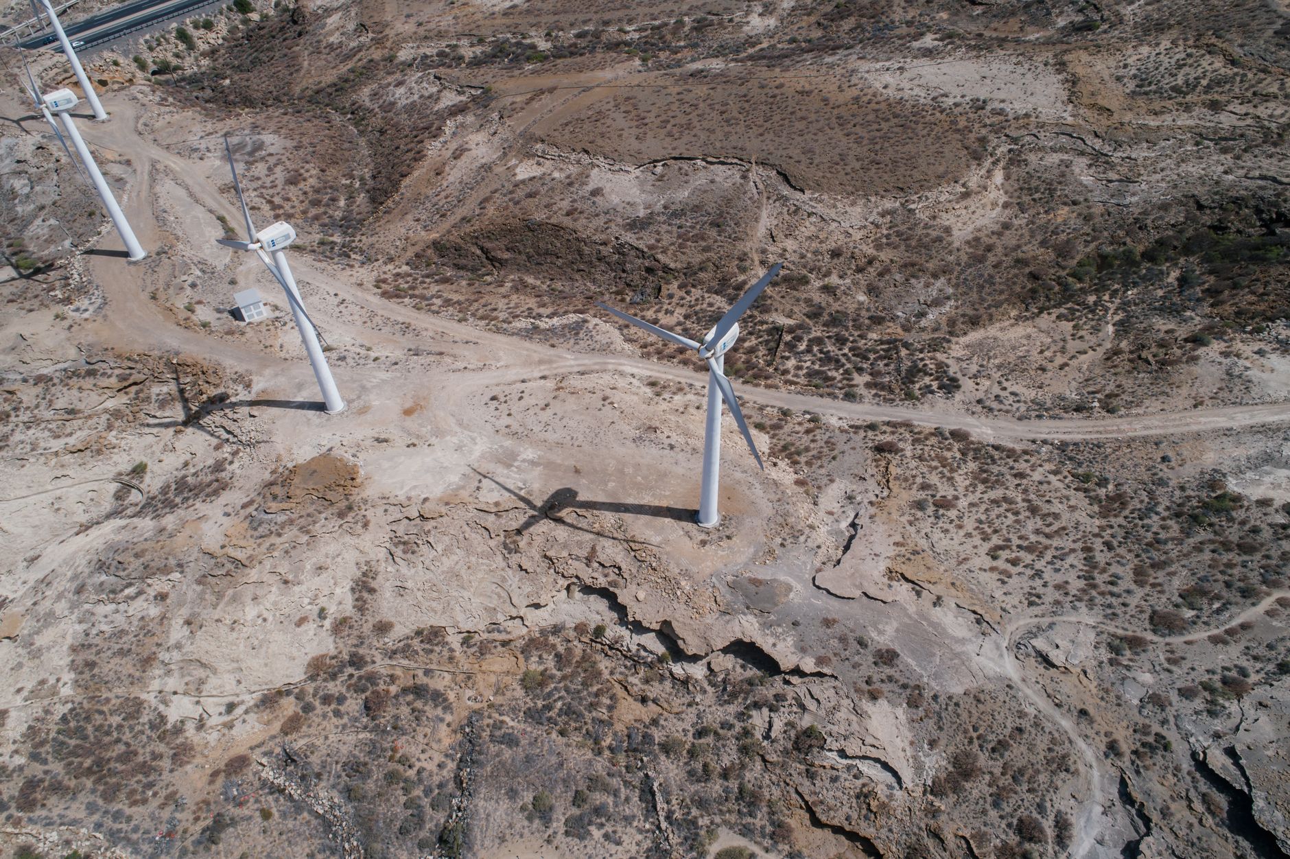 Drone shot of wind turbines generating renewable energy in a barren rocky landscape.