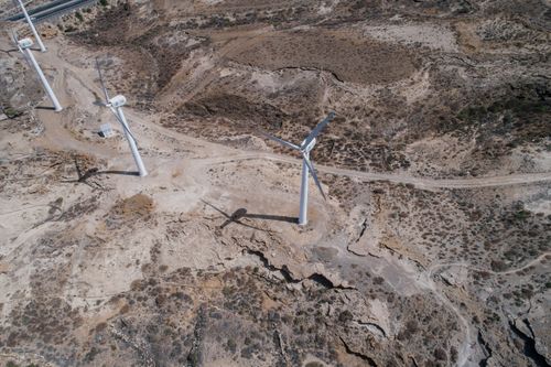 Free Drone shot of wind turbines generating renewable energy in a barren rocky landscape. Stock Photo