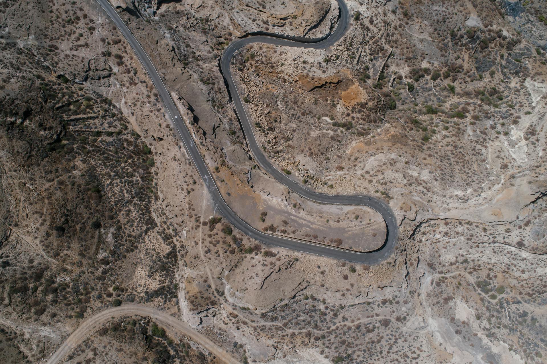 Drone shot of a winding road in a rocky desert landscape. Perfect for travel and adventure themes.