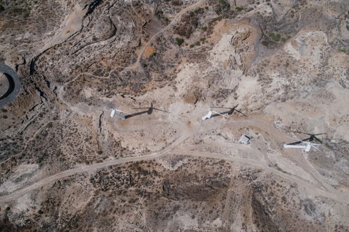 Free Aerial view of wind turbines across an arid landscape, showcasing renewable energy in remote terrain. Stock Photo