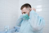 Man in White Scrub Suit Holding White Plastic Container