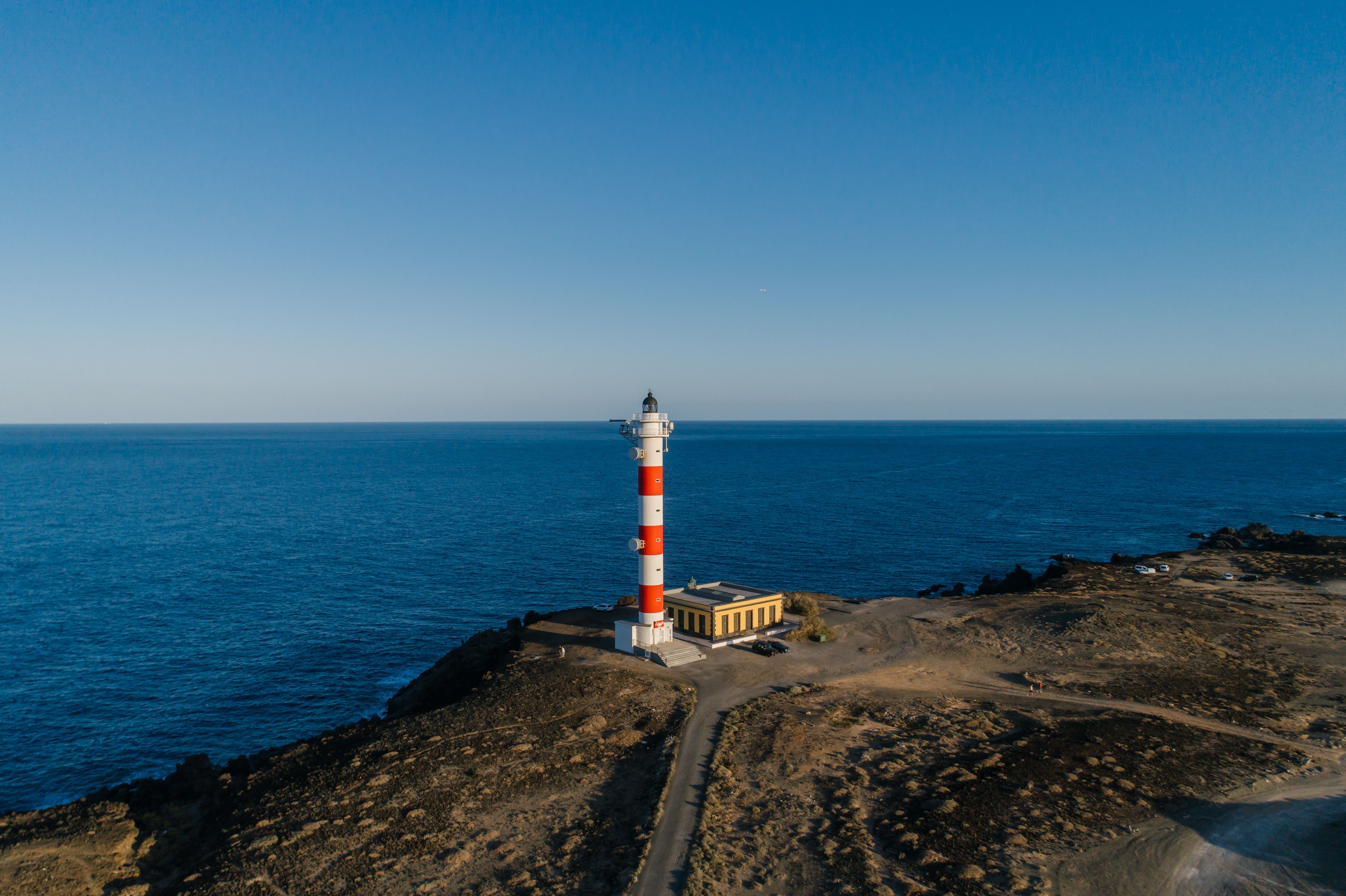 White and Red Lighthouse Near Body of Water · Free Stock Photo