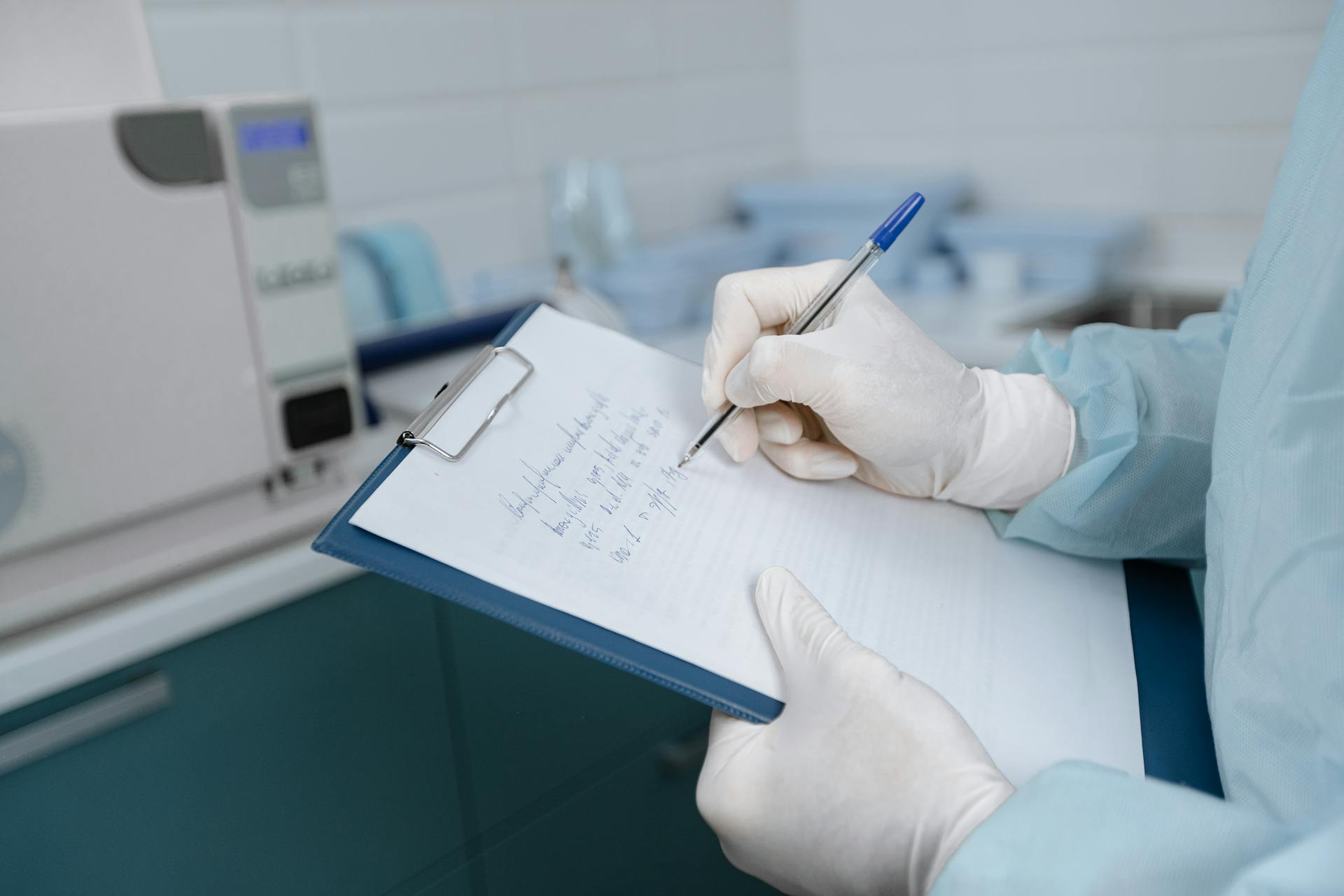 Medical worker in lab coat writing notes in a clinic setting.