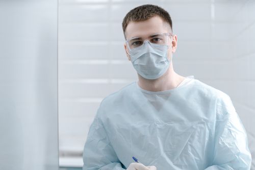 Free Medical professional wearing protective gear, including face mask and goggles, indoors. Stock Photo