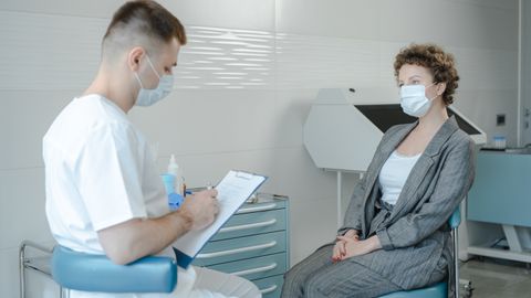 A doctor in a face mask consults a patient in a clinic, reflecting the new normal.