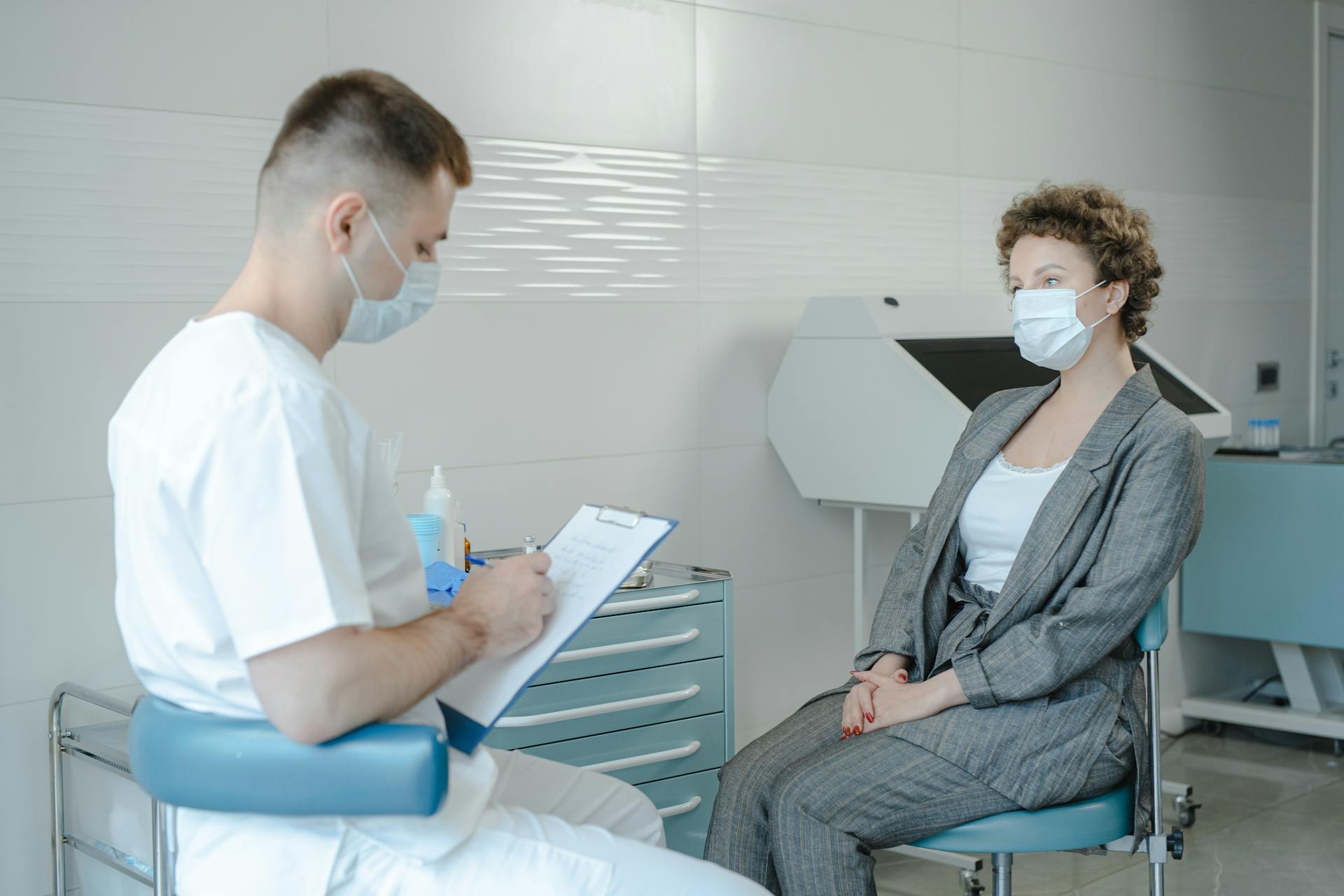 A doctor in a face mask consults a patient in a clinic, reflecting the new normal.